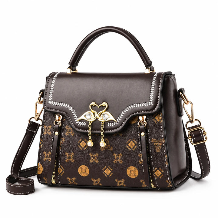 Brown small crossbody bag with patterned front, curved flap and twin-swan ornament on white.