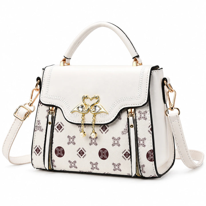 Ivory square crossbody bag with patterned front and flap closure on a white background.