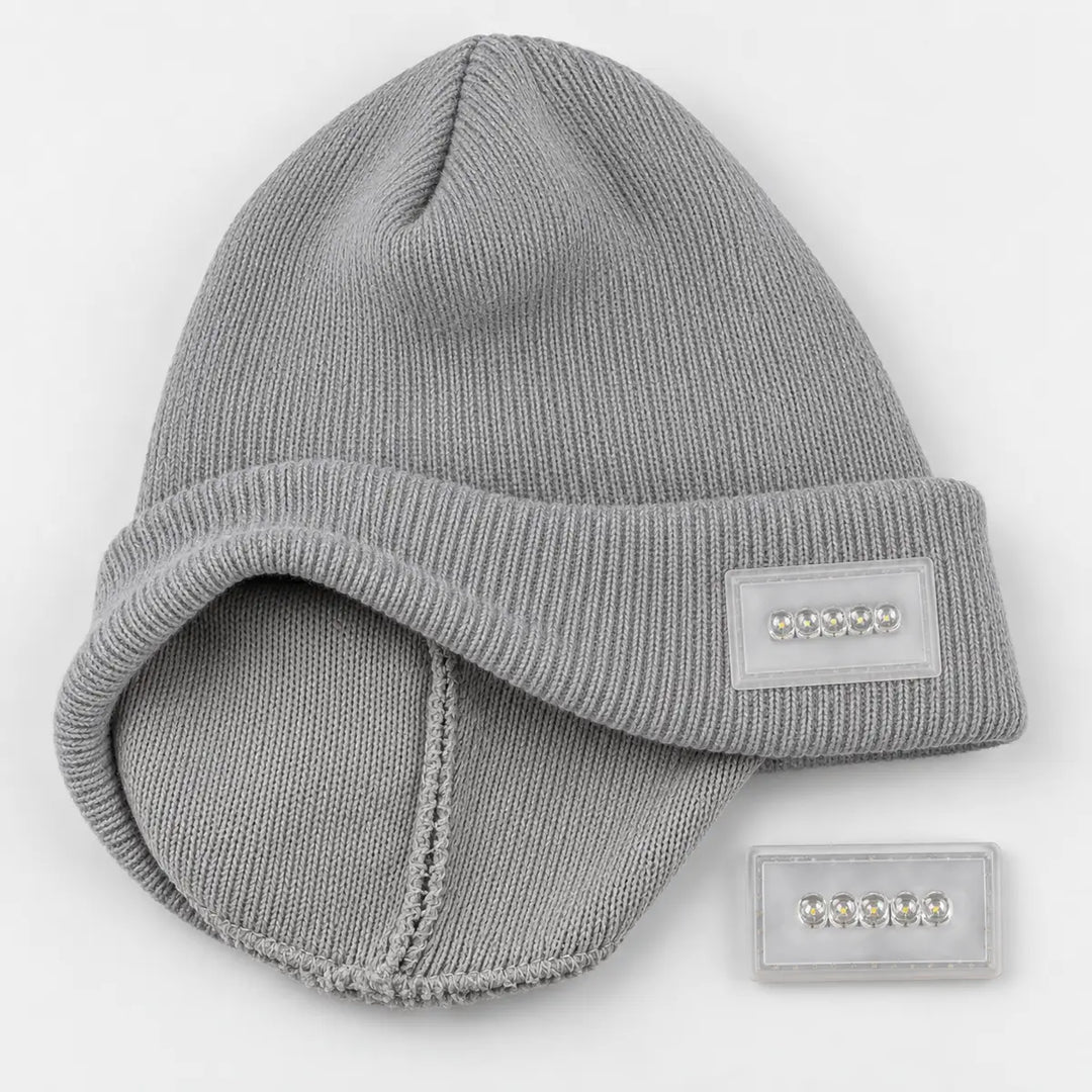 Reversible knit beanie shown in a flat lay with the inside construction, folded cuff and removable five-light module visible.