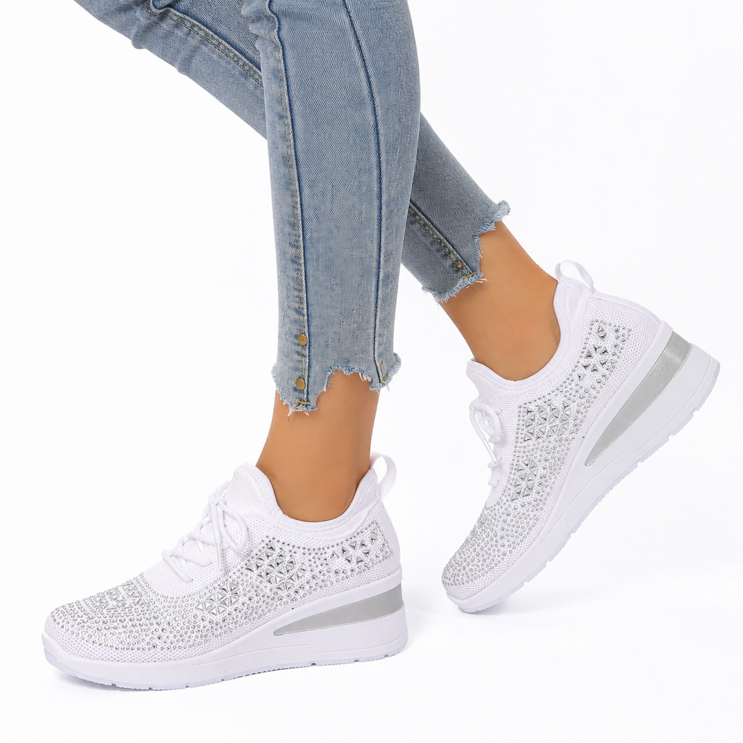 White rhinestone wedge sneakers on a woman against a clean white studio background.