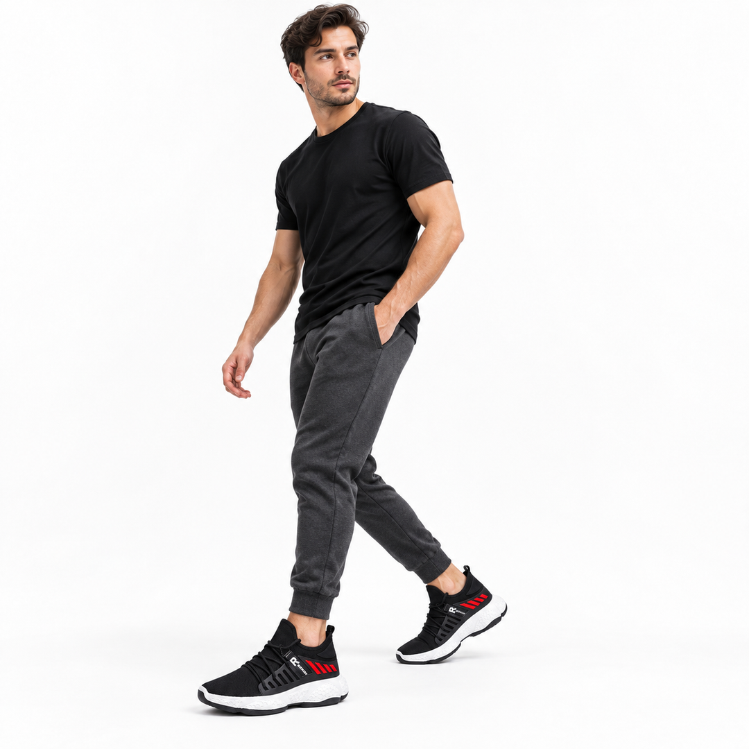 Male model wearing black mesh running shoes with red accents and white EVA soles for a simple casual athletic look.