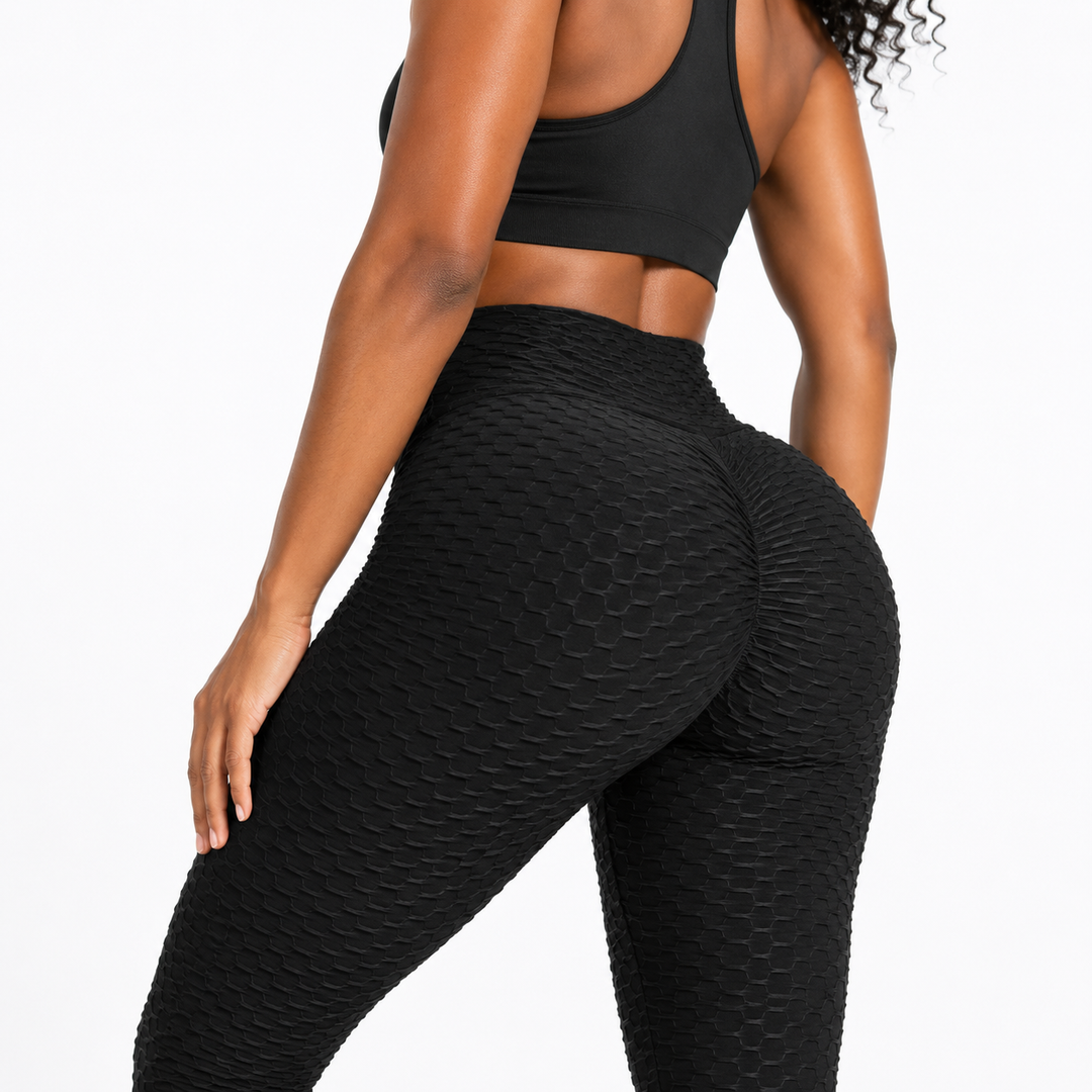 Close-up of black scrunch leggings on an adult model, showing the textured surface, high waistband and visible seam details.