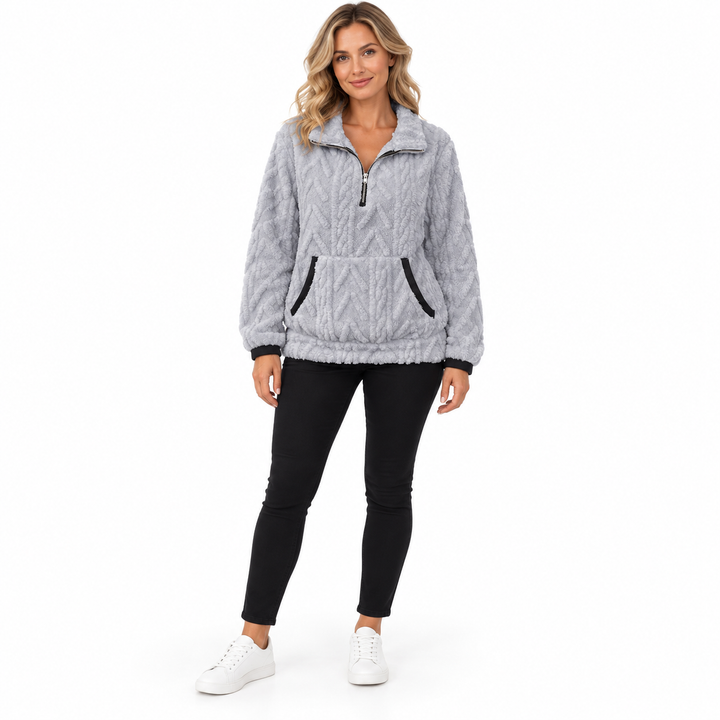 Light gray sherpa sweatshirt on a blonde model in black trousers and white sneakers, with black pocket trim and zip neckline.