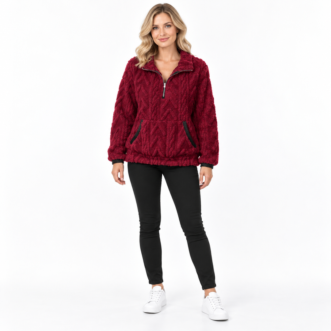 Burgundy textured zip-neck pullover on a blonde model in black trousers and white sneakers, showing collar and front pockets.