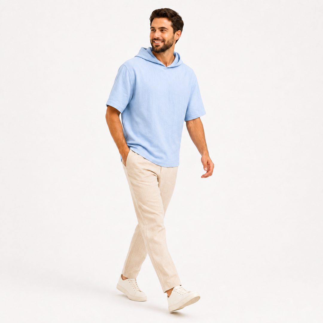 Man wearing a sky blue short sleeve pullover hoodie in a full-body walking pose on white.