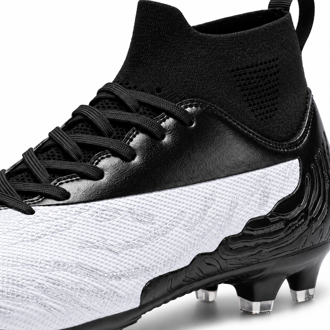 Close-up of white and black soccer cleat showing textured upper, black laces, knit ankle collar and sculpted heel details.