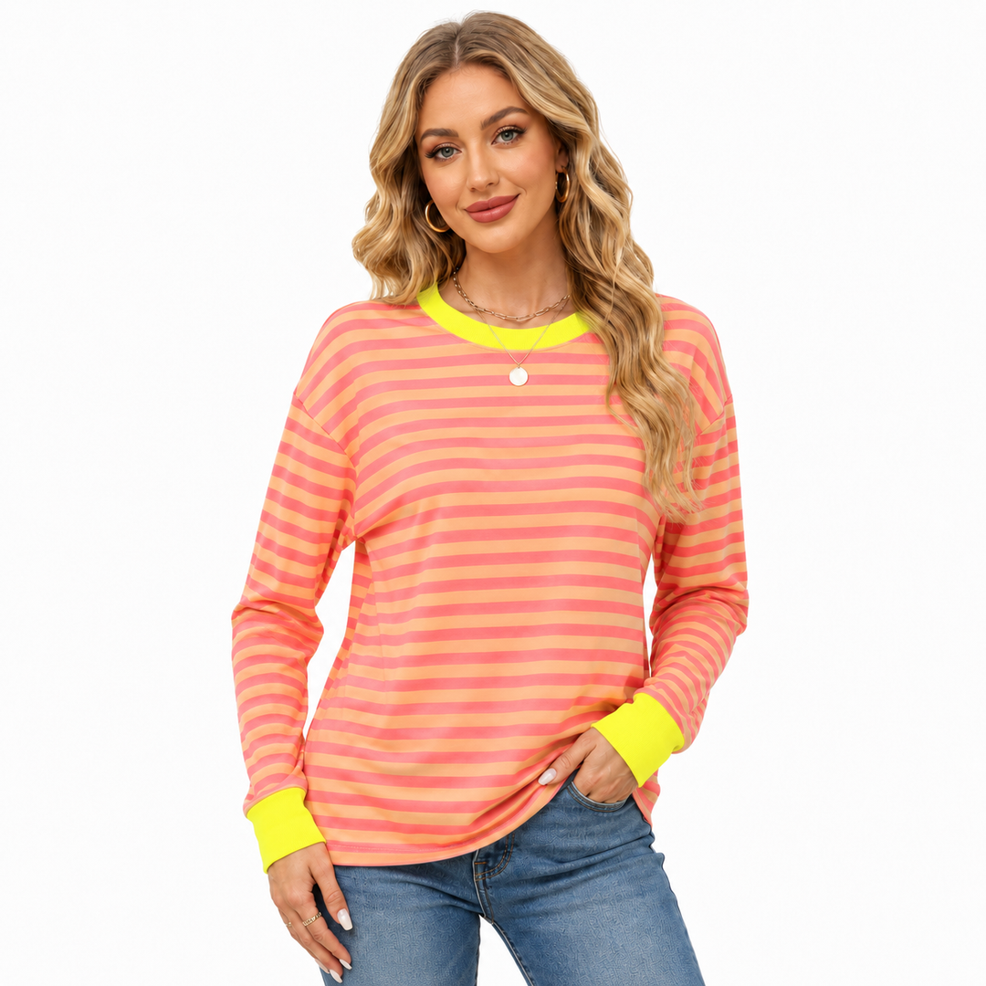 Women's coral and peach striped long sleeve top with neon yellow neckline and cuffs, modeled with blue jeans on white studio.