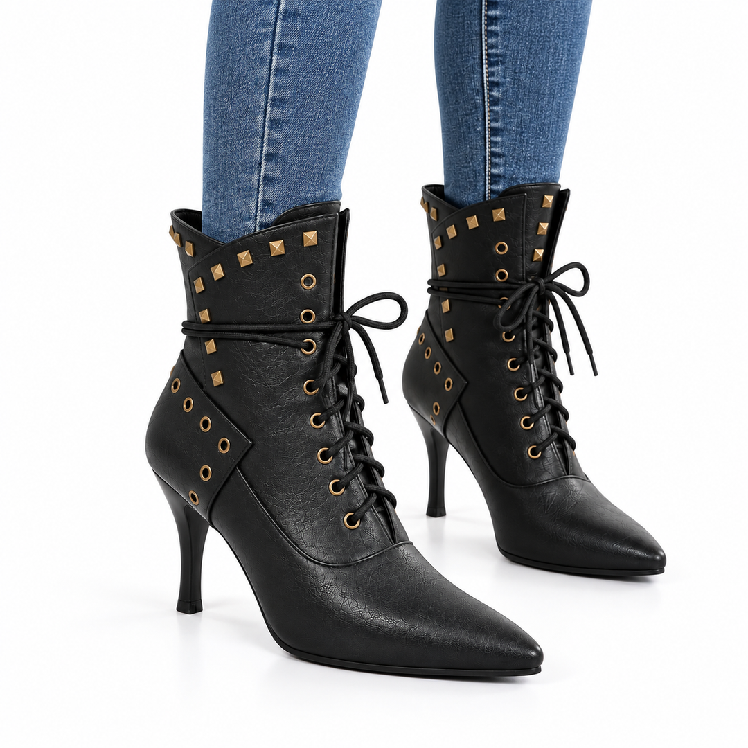 Black studded ankle boots styled with slim blue jeans on a clean white background