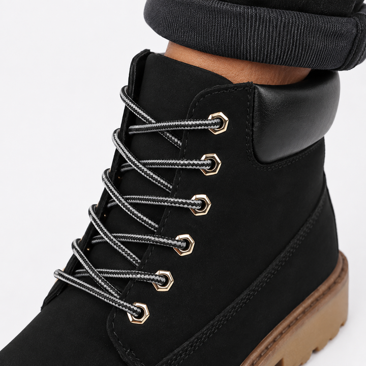 Black high-top casual boot close-up showing laces, metal eyelets, padded collar, tongue and stitching