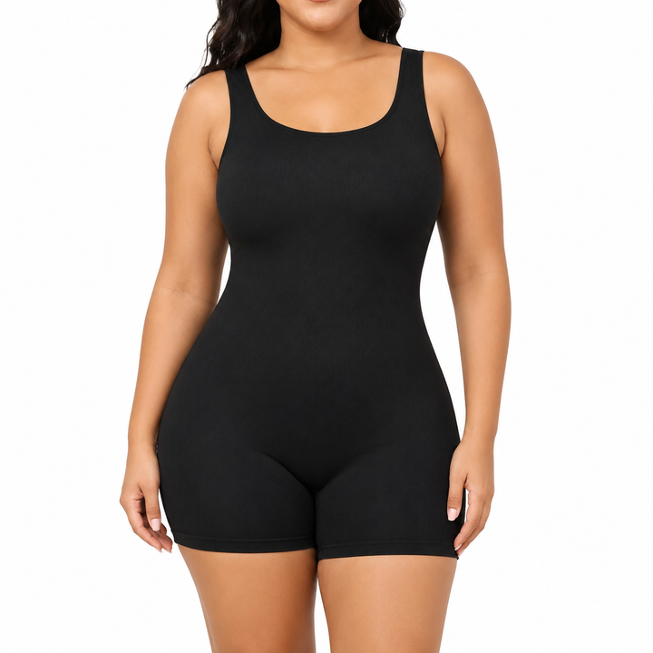 Tummy control bodysuit in black on a model, front studio view with scoop neckline, wide straps and mid-thigh shorts on white.