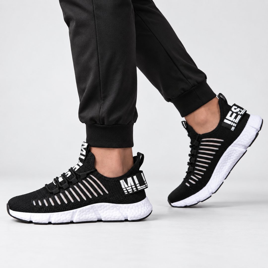 Midnight black casual sneakers shown from the side on a model, highlighting the low-top silhouette and segmented white sole.