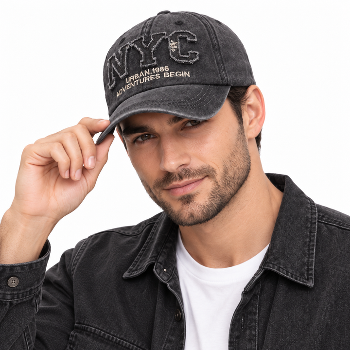 Man wearing the charcoal black adjustable NYC baseball cap with embroidered front detail against a clean white studio background.