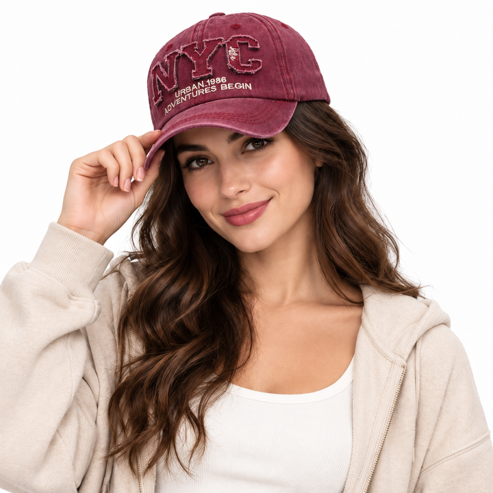 Woman wearing the burgundy adjustable NYC baseball cap in a clean white studio setting with the embroidered front clearly visible.