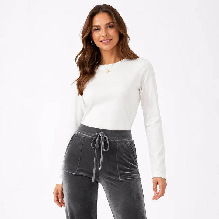 Close-up front view of dark gray velvet flare pants with model face showing the high waistband, drawstring and patch pockets.