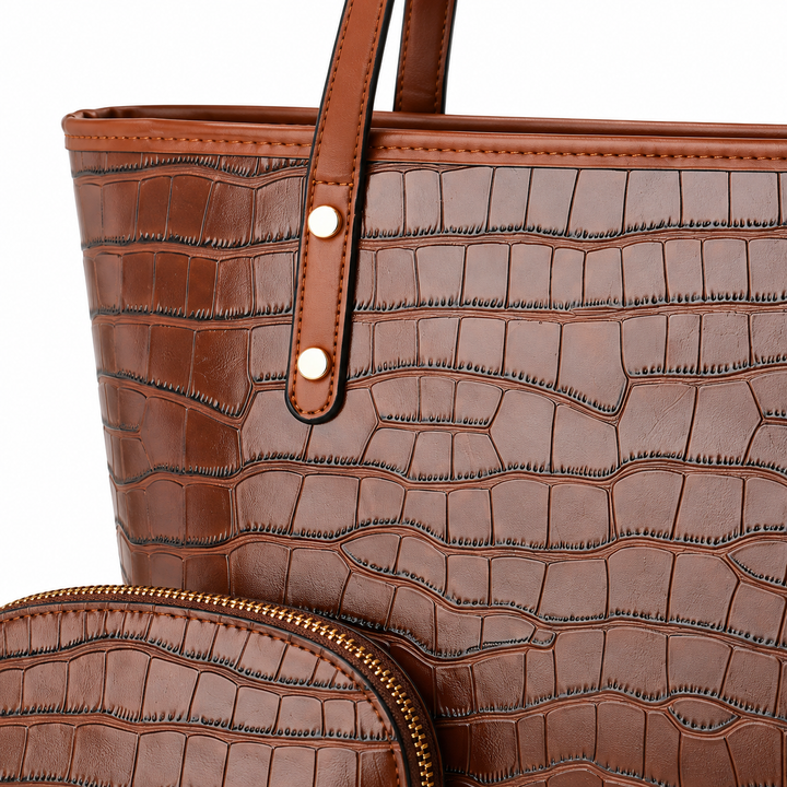 Brown crocodile-embossed tote bag close-up showing strap rivets, trim and matching pouch zipper