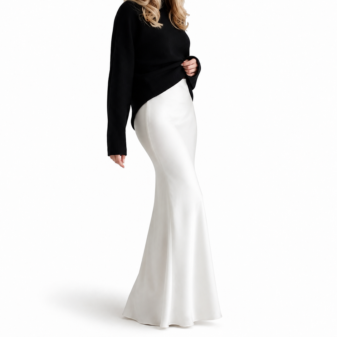 Side view of white high-waisted maxi skirt on model, highlighting fitted waist and hips, long drape and softly flared hem.