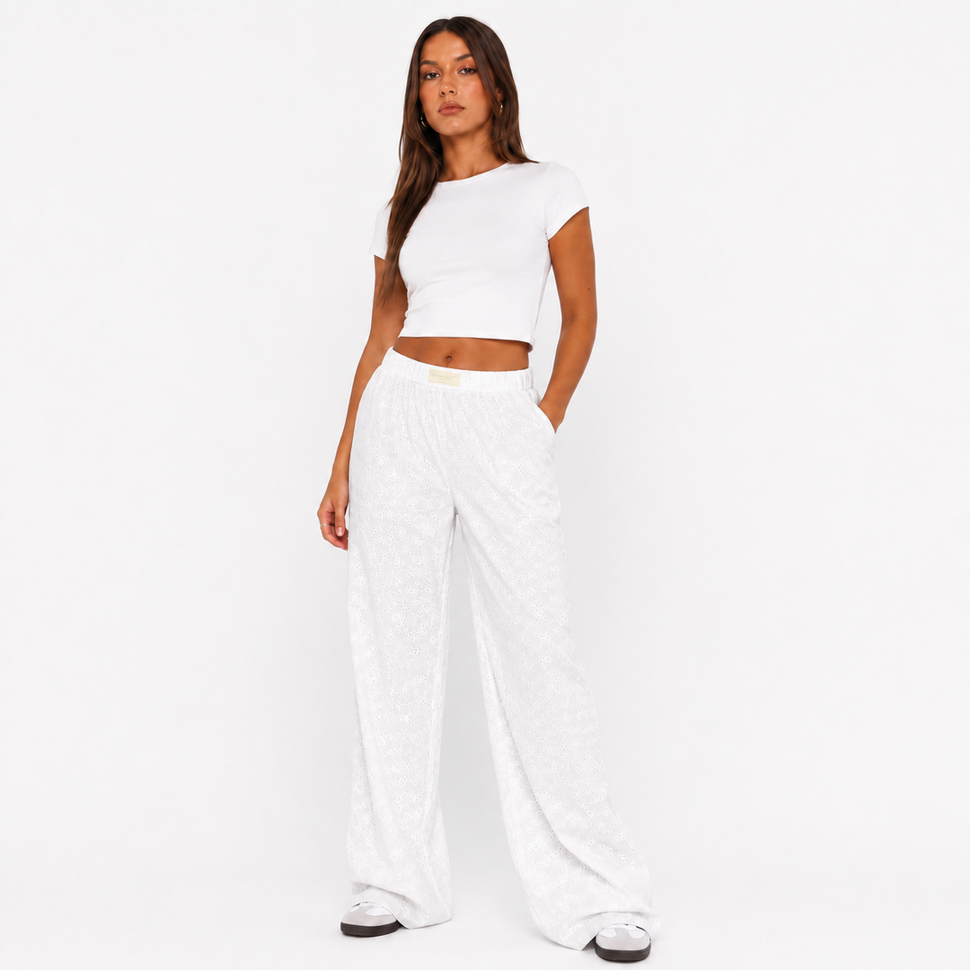 White wide leg pants for women on a studio model, showing elastic waist, textured fabric and relaxed full-length silhouette.