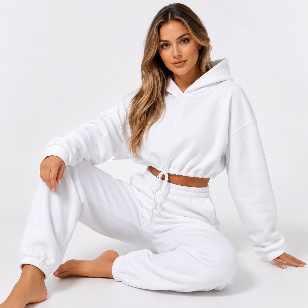 Women's white hoodie and jogger set shown on a female model in a seated studio pose against a clean white background.
