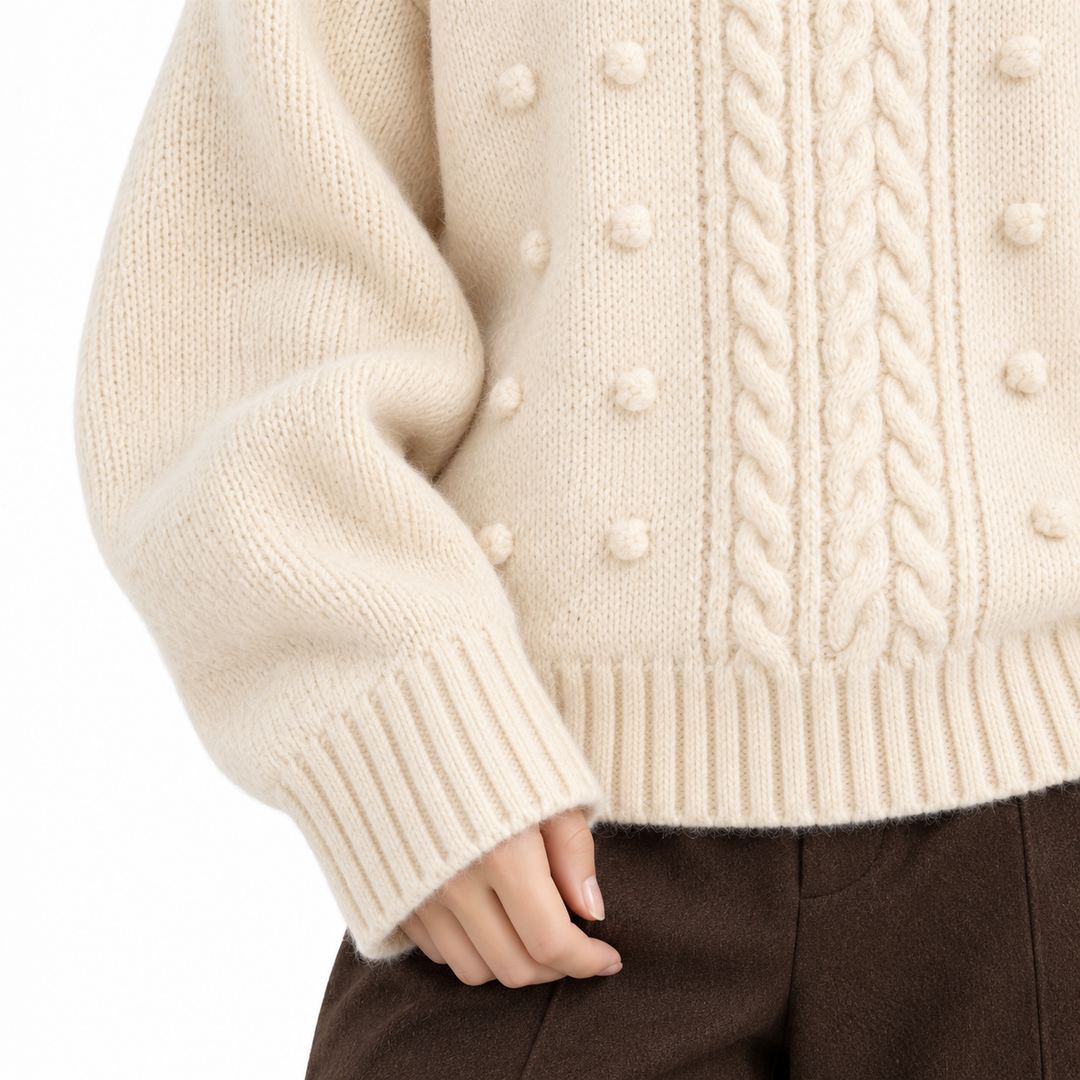 Ivory knit sweater close-up showing cable texture, bobble detail and ribbed finish