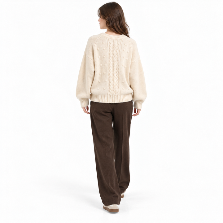 Ivory cable knit sweater shown from the back with long sleeves and ribbed hem