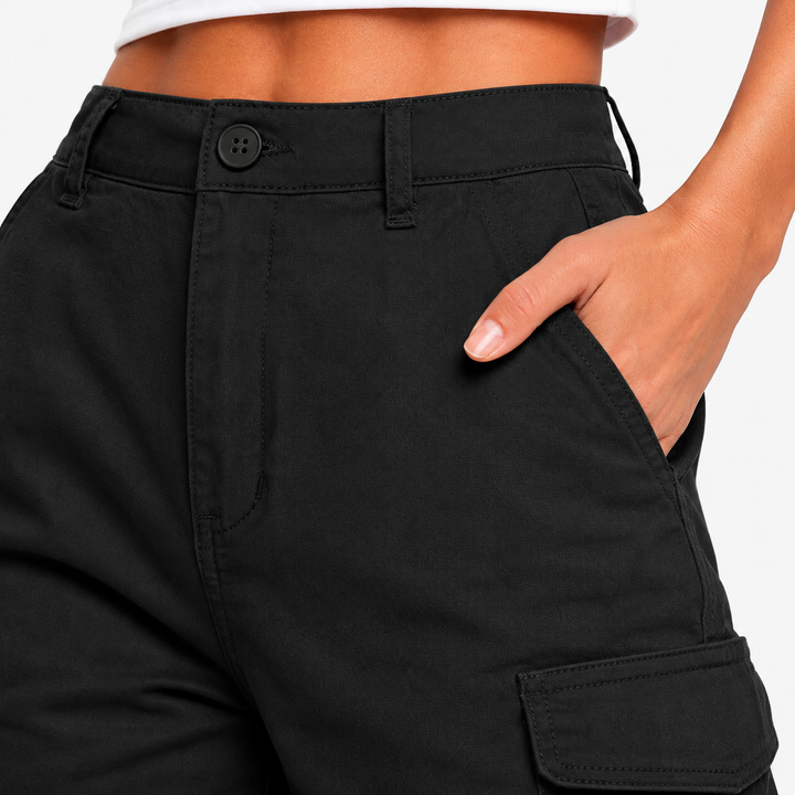 Close-up of black multi-pocket shorts showing the waistband, stitching and pocket construction in a clean studio detail view.
