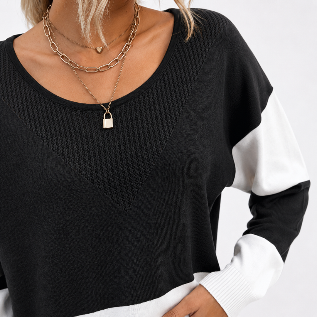 Close-up of the black and white color block ribbed sweater showing the round neckline, textured chest panel and ribbed cuff.