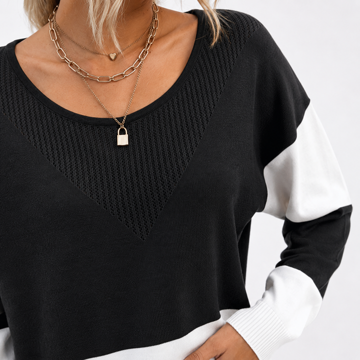 Close-up of the black and white color block ribbed sweater showing the round neckline, textured chest panel and ribbed cuff.