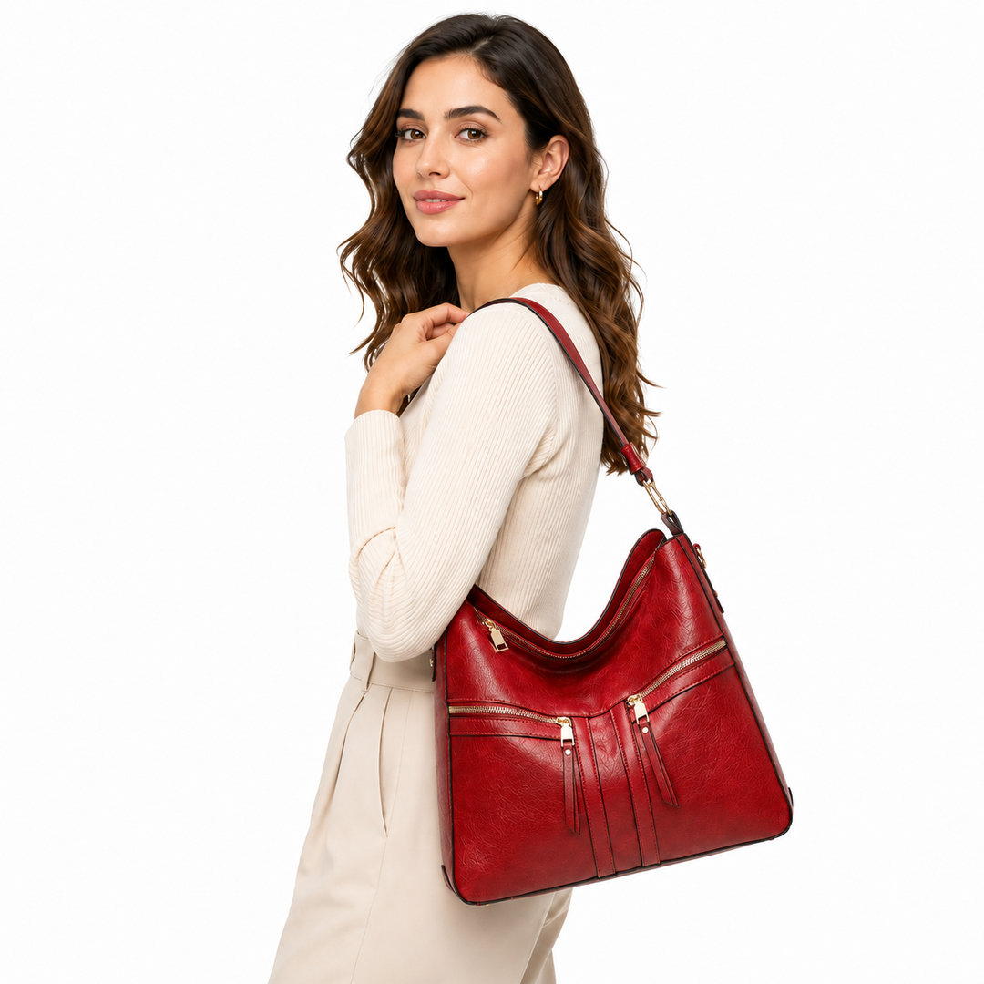 Faux leather tote bag in red carried by a woman on white, with double zipper pockets and full shoulder carry profile visible.