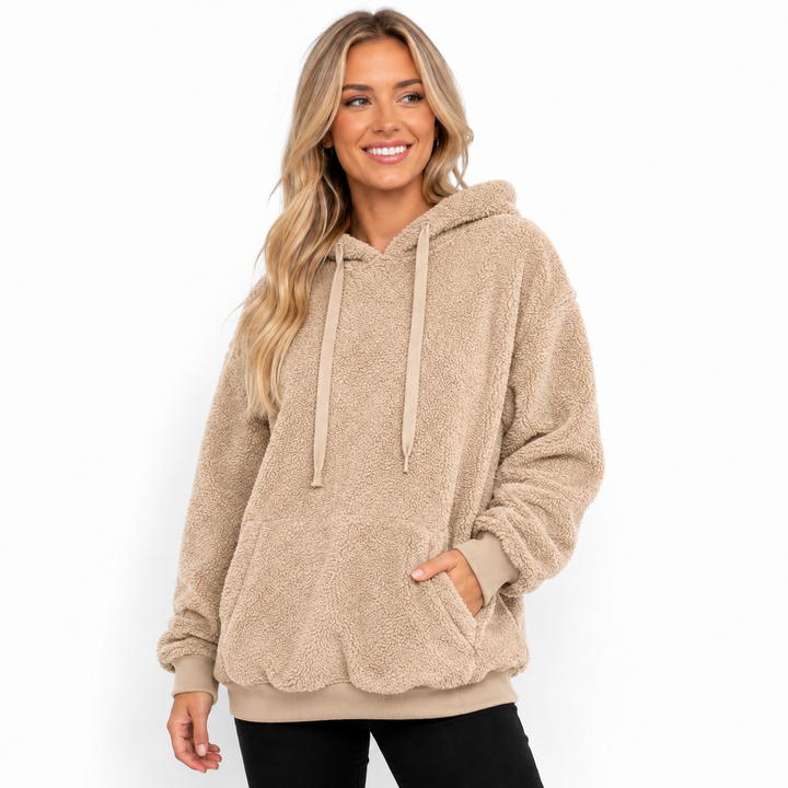 Beige hooded fleece pullover on a model showing textured surface, drawstrings, kangaroo pocket and ribbed finishing on white.