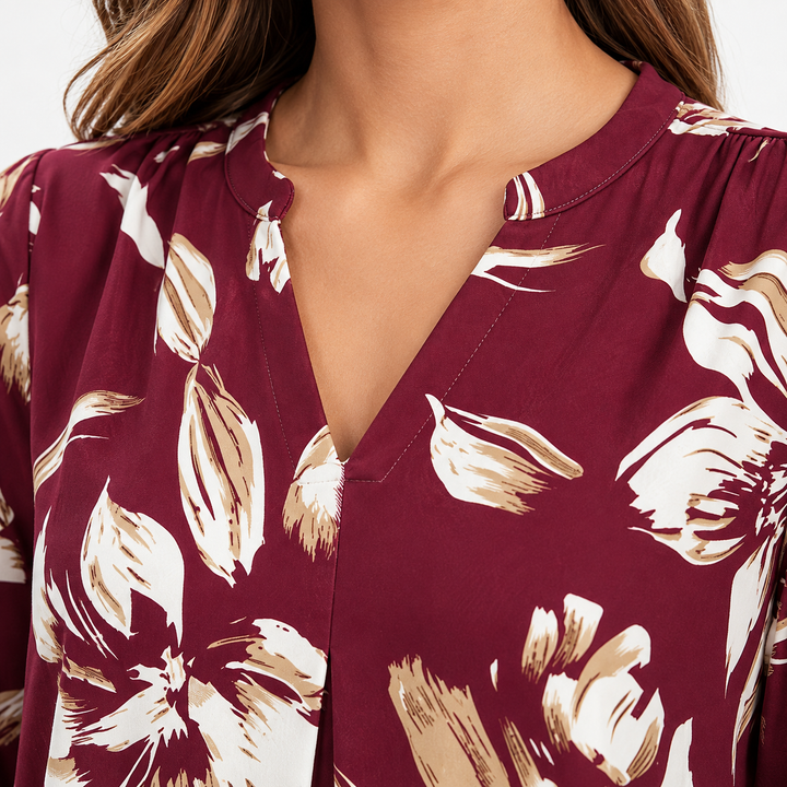 Close-up of the burgundy floral blouse V-neckline showing printed floral details, neckline construction and stitching in studio view.