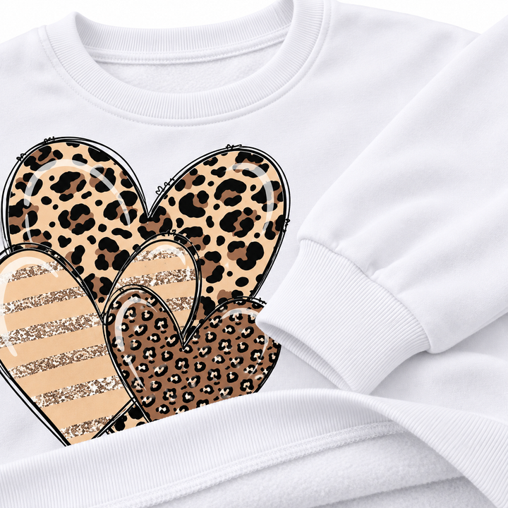 Close-up of the White top showing the crew neckline, cuff, hem and leopard heart print details.