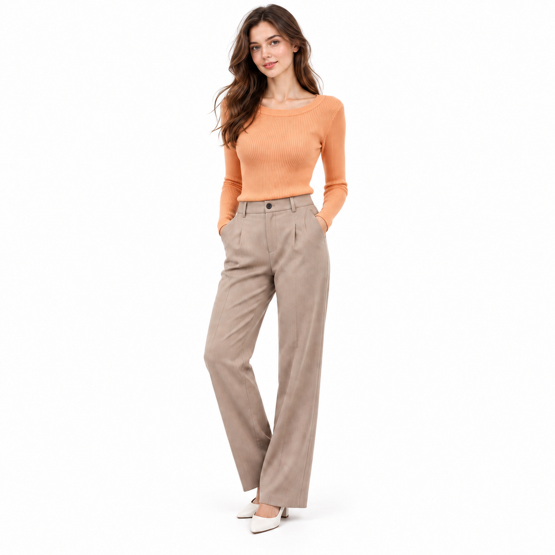 Orange ribbed long sleeve knit top on a full-body model with neutral trousers and a clean white background.