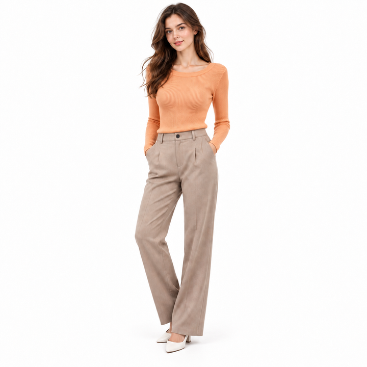 Orange ribbed long sleeve knit top on a full-body model with neutral trousers and a clean white background.