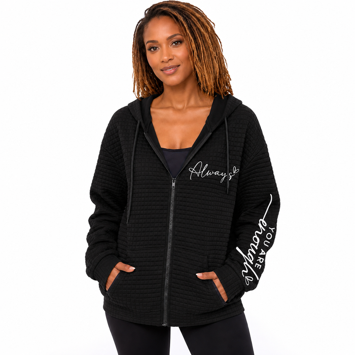 Black letter zip hoodie on model with hood, pockets, chest script and sleeve graphic against a clean white studio background.