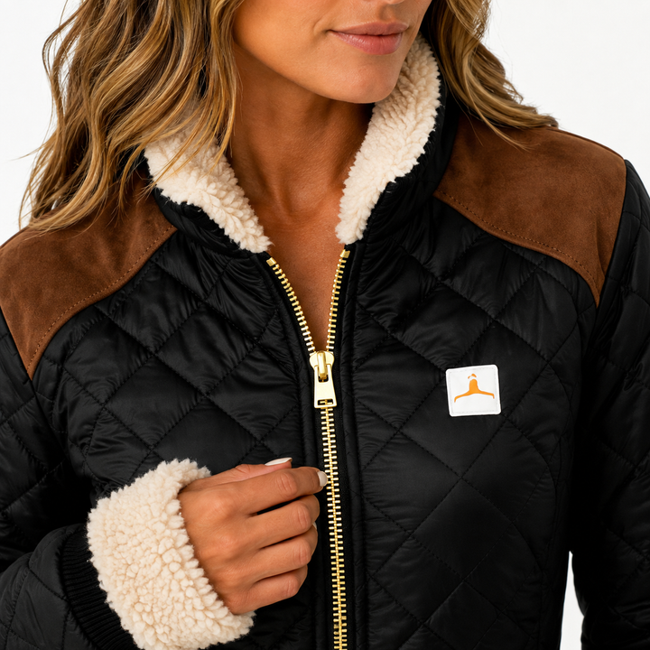 Detail view of quilted jacket collar and zipper, cream cuff trim, brown shoulder panels and small chest patch on black fabric