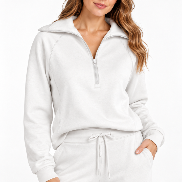White matching tracksuit close-up showing the zip neckline, long sleeves and drawstring waist against a clean studio background
