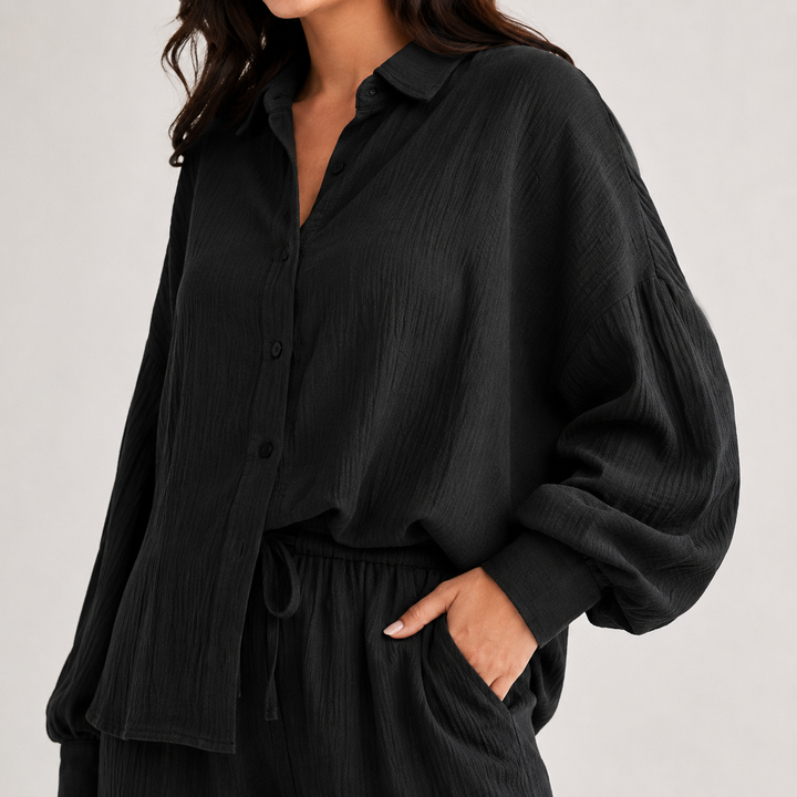 Close-up of black textured two-piece set showing collared button shirt, waistband drape and side pocket