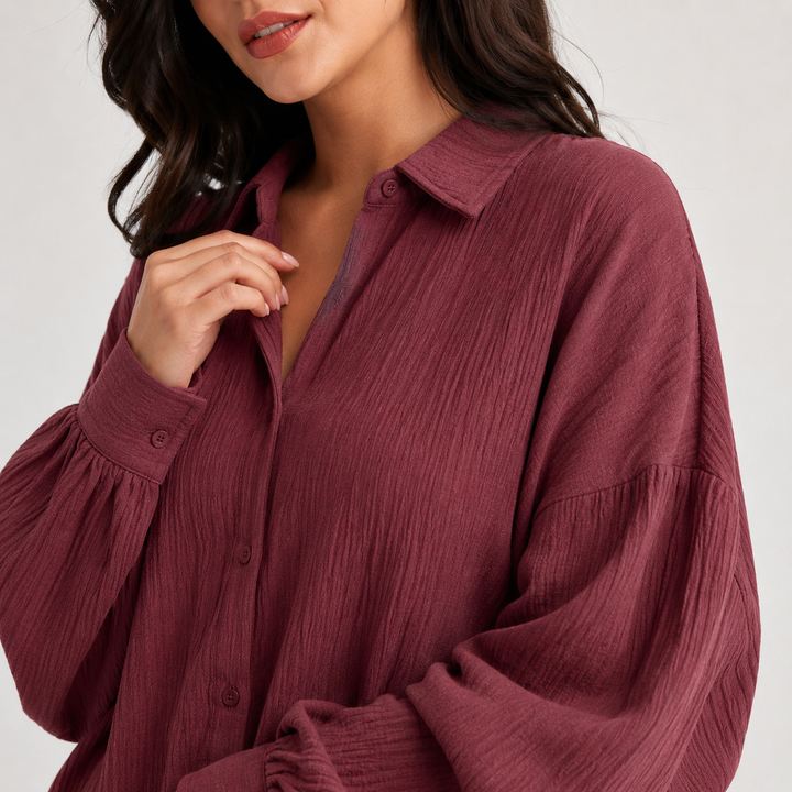 Close-up of burgundy textured fabric, collar, buttons and sleeve detail on the women&