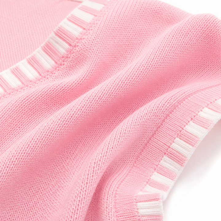 Macro close-up of blush pink knit fabric and contrast edging, showing knit texture, stitching and clean product finishing.